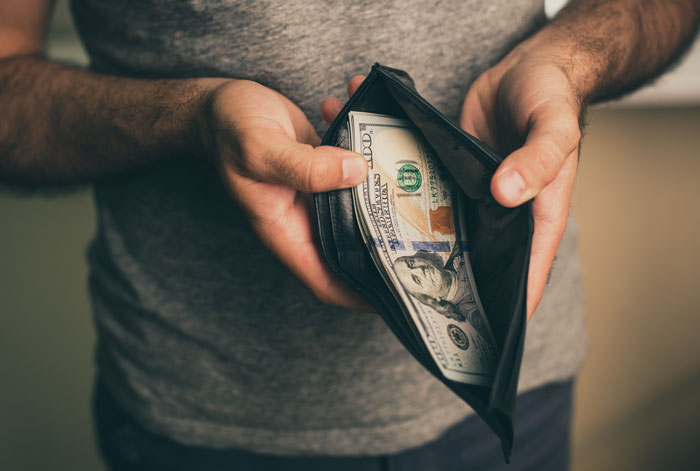 man holding open wallet with cash inside